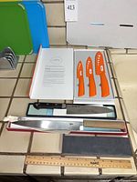 Overview showing cutting boards on stand, Imori ceramic knife set, boxed Kikuhide knives and assorted loose knives