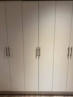 Front view showing full height double-door white cabinet with metal handles