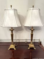 Front view of both brass lamps with shades on tabletop