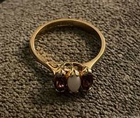 Full view of ring on textured surface showing three-stone setting and band