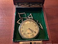 Pocket watch and chain inside green-lined wooden case