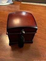 Front view of small wooden musical jewellery box with tassel