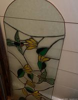 Full view of arched stained glass panel with floral and hummingbird motif