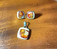 Front view of pendant and earrings showing design and colors