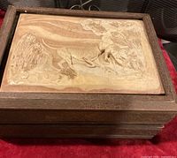 Top view of closed wood case showing hunting dog relief plaque