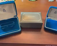 Two Birks blue velvet cases flanking Christian Dior grey box