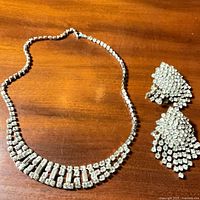 Full view of rhinestone necklace and both earrings on wood surface