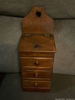 Front view showing entire wooden wall box with lid and three drawers