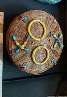 Top view of wicker sewing basket showing lid decoration and yellow ring handles