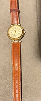 Full view of watch showing case and full length of leather strap with visible mark