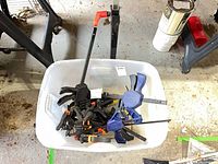 Bin on garage floor containing various clamps