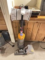 Full view Dyson upright vacuum with yellow cyclone and clear canister