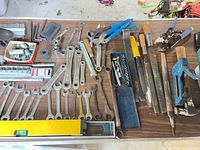 Wide view of table with wrenches, sockets, pliers, files, staple gun, level