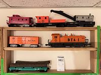 Five Lionel O gauge train items on shelves