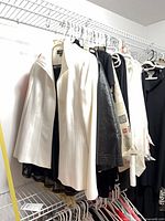 Closet rack with white blazer, black garments, printed blazer