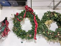 Two artificial wreaths on wall, extension cord at left
