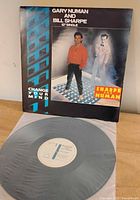 Front of sleeve showing title and artists with vinyl partially visible