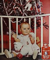 Close-up of advertisement showing baby, plush toy, Cow & Gate tin, Christmas tree