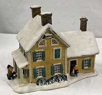front view showing snow-covered roof, chimneys, porch, figurine