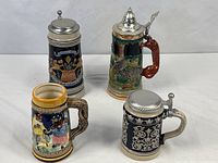 Group shot of four ceramic beer steins showing relative sizes and decoration