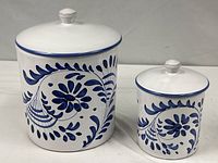 Both ceramic canisters with lids displayed side by side