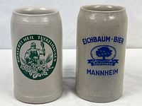 Front view of both stoneware beer steins showing brewery logos