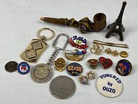 All items laid out showing pipe, pins, keychains, token and figurine