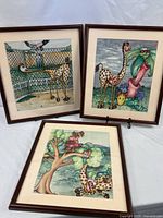 Group shot of three framed giraffe paintings