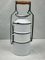 Full view of stacked white enamel tiffin carrier with frame and handle