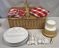 all items laid out: basket, napkins, plates, utensils, containers, cheese board, corkscrew