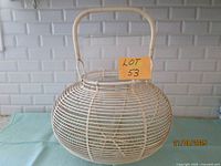front view of round white wire egg basket with handle and lot card