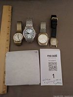 Group shot of all four watches with ruler for scale