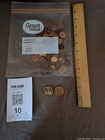 Bag of pennies, two loonies beside ruler for scale