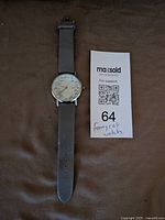 Front view of watch showing dial, strap and lot tag