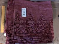 Folded burgundy shawl with embroidered border and ruler for scale