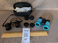 Overview of binoculars, magnifier, caps, case with ruler for scale