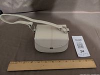 Closed cream leatherette jewelry case beside ruler showing scale