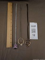 All three necklaces laid out beside ruler for length reference