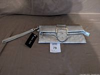 Front view of silver quilted clutch with wrist strap and buckle