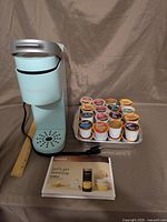 Coffee maker, tray of pods, manual and ruler for scale