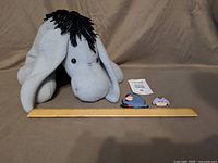 Front view of plush Eeyore alongside ruler and two pins