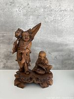 Full view of carved wood deity and child sculpture on base