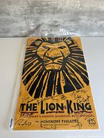 Full view of cast-signed Lion King Minskoff Theatre poster in plastic sleeve