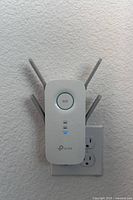 Front view of TP-Link RE650 plugged into wall outlet showing LED indicators and antennas