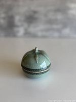Front view of celadon incense burner showing leafy finial and band decoration