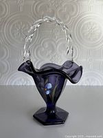 Front view showing amethyst glass body, clear twisted handle, floral painting