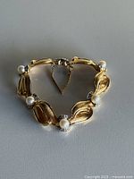 Full view of gold-tone bracelet showing pearls, leaf links, clasp, safety chain