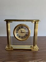 Front view brass and glass table clock showing dial and columns