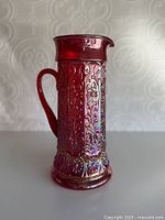 Front view of ruby red carnival glass pitcher showing spout and pattern
