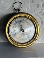 Full view of brass marine barometer with hanging ring